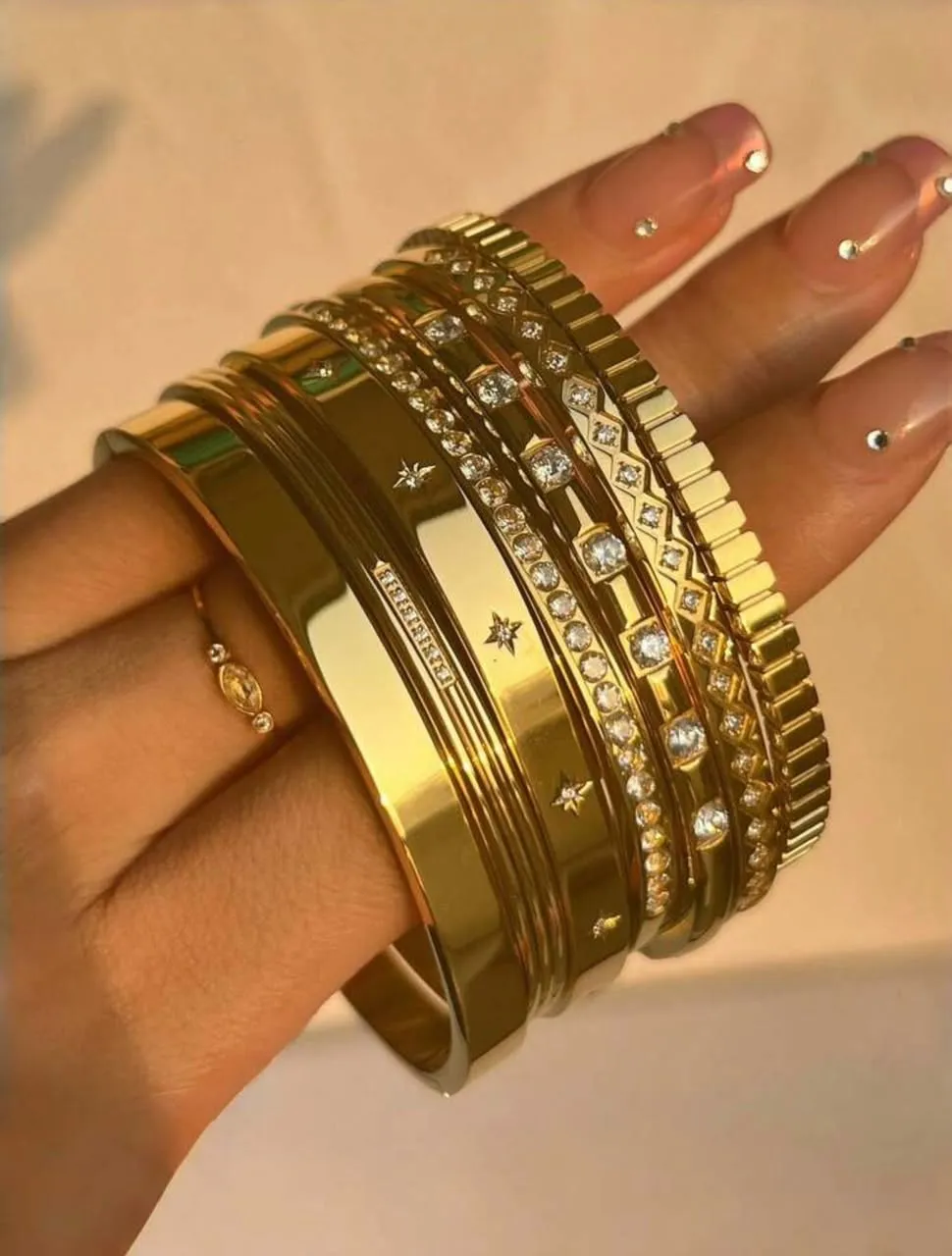 Mano luciendo un conjunto de brazaletes dorados de ONTREND.VE